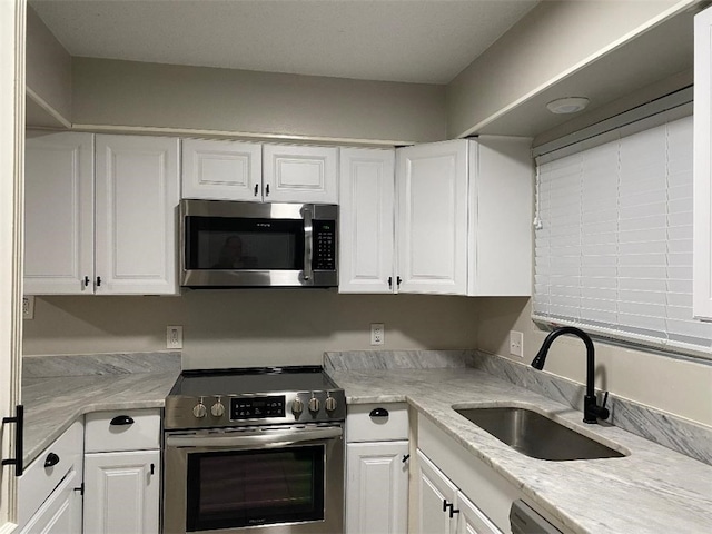 kitchen featuring light stone counters, white cabinetry, sink, and appliances with stainless steel finishes