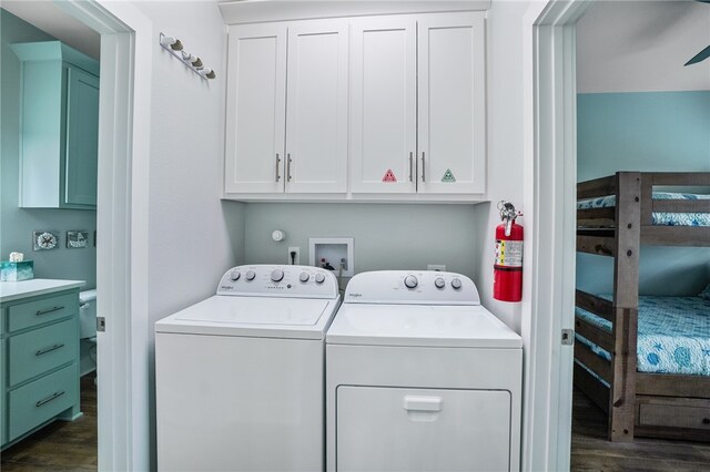 washroom with washing machine and clothes dryer, cabinets, and dark wood-type flooring