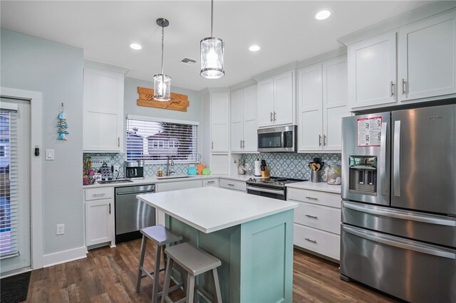 kitchen featuring stainless steel appliances, white cabinetry, dark hardwood / wood-style flooring, and a center island