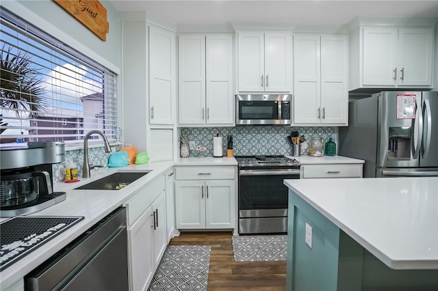 kitchen featuring stainless steel appliances, sink, backsplash, white cabinets, and dark wood-type flooring