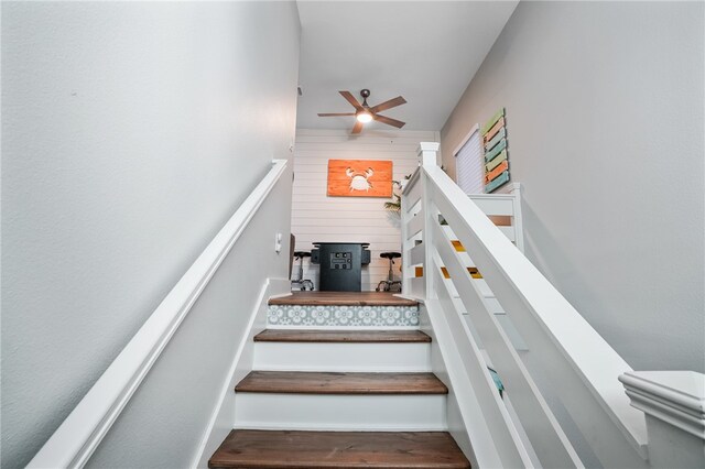 stairway featuring wood walls and ceiling fan