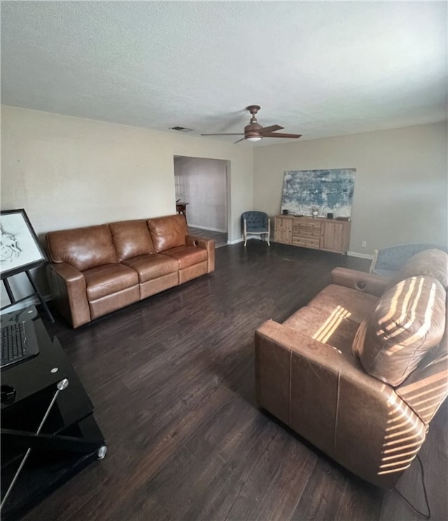 living room featuring dark wood-type flooring, ceiling fan, and a textured ceiling