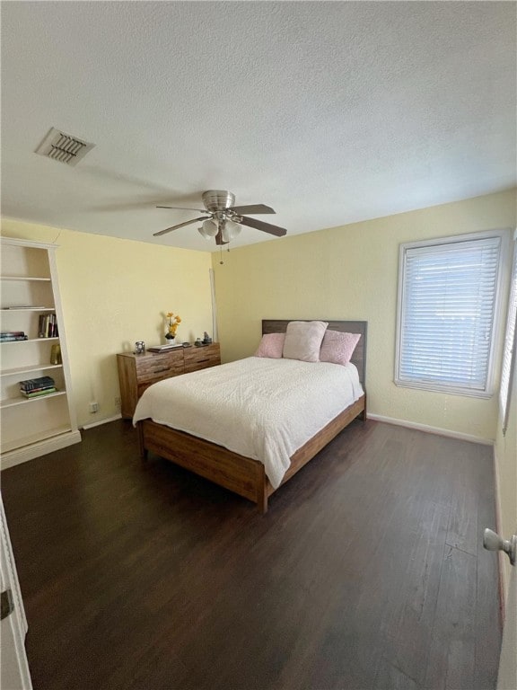 bedroom with dark wood-type flooring, ceiling fan, and a textured ceiling