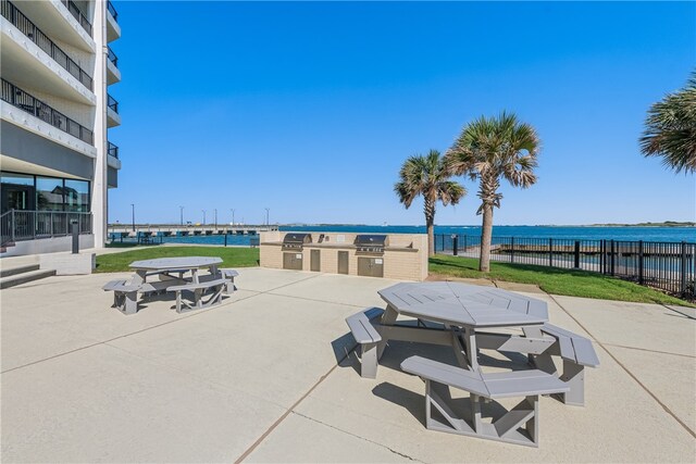 view of community with a yard, a patio, and a water view