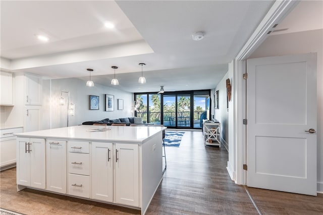 kitchen featuring expansive windows, dark wood-type flooring, a center island, white cabinets, and decorative light fixtures