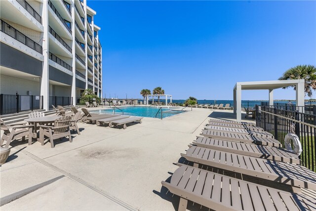 view of pool featuring a water view and a patio