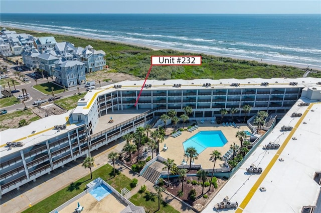 bird's eye view of apartment complex, extended coastline, and a pool area