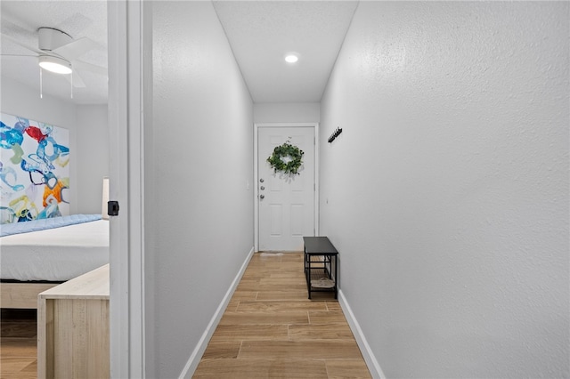 hall featuring light wood-style flooring and baseboards