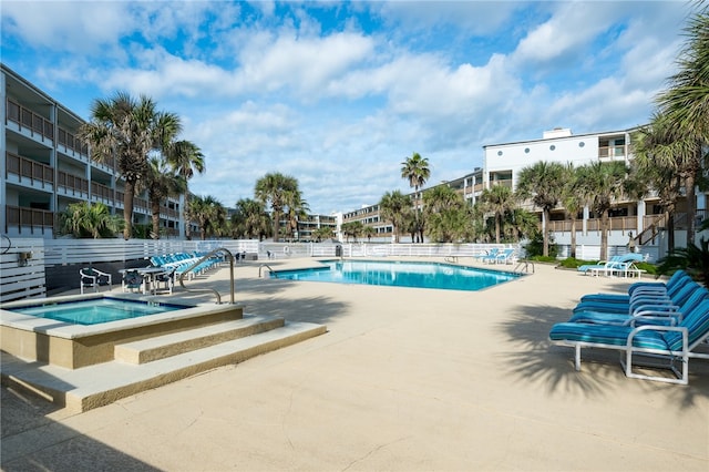 pool featuring a community hot tub, a patio, and fence