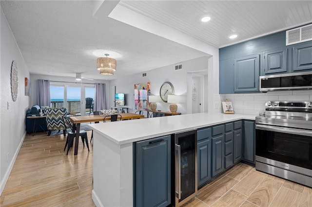 kitchen featuring wine cooler, a peninsula, visible vents, appliances with stainless steel finishes, and wood tiled floor