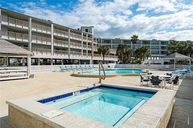 pool with a patio, a community hot tub, and a gazebo