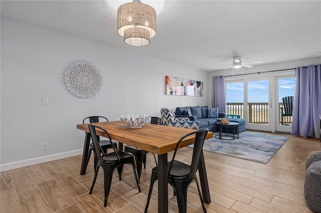 dining area with ceiling fan with notable chandelier, light wood finished floors, a textured ceiling, and baseboards