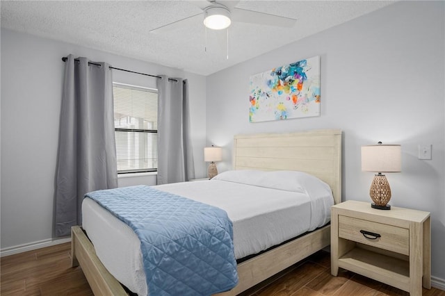 bedroom featuring ceiling fan, a textured ceiling, baseboards, and wood finished floors