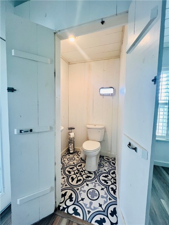 bathroom featuring wood walls, wood-type flooring, and toilet