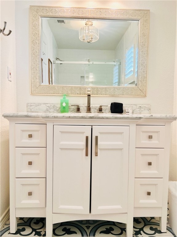 bathroom with vanity, an inviting chandelier, and a shower with shower door