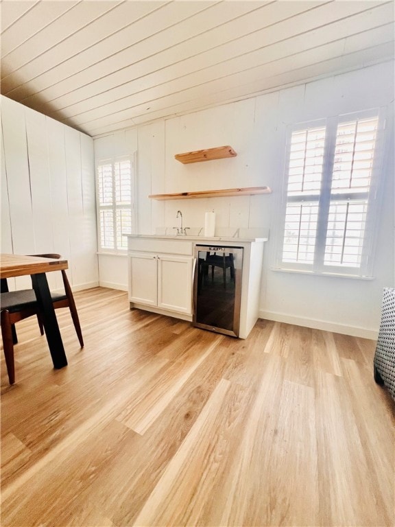 bar with white cabinetry, stainless steel dishwasher, light hardwood / wood-style floors, and plenty of natural light