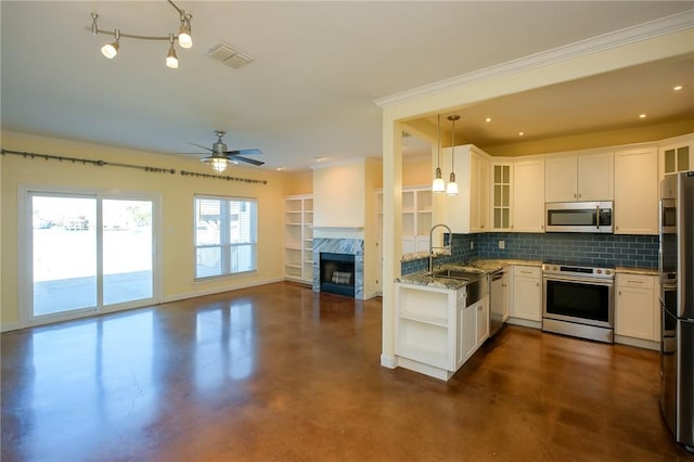 kitchen featuring backsplash, white cabinets, stainless steel appliances, and decorative light fixtures