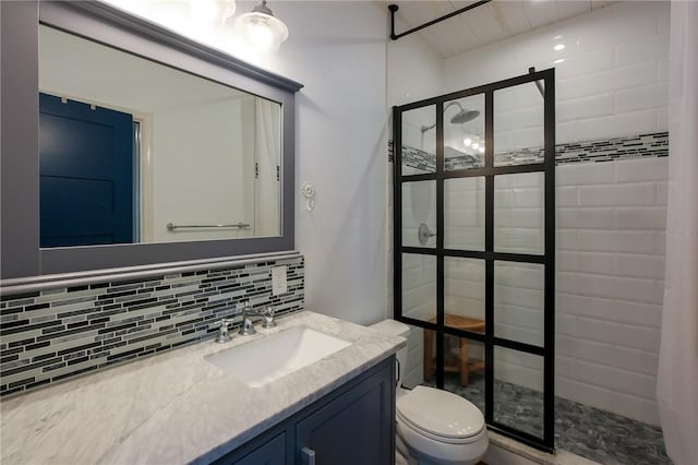 bathroom with decorative backsplash, toilet, a tile shower, and vanity