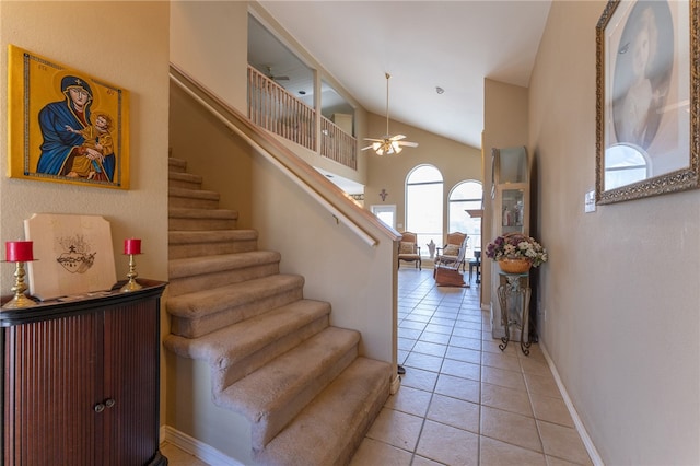 stairs with high vaulted ceiling, tile patterned flooring, and ceiling fan