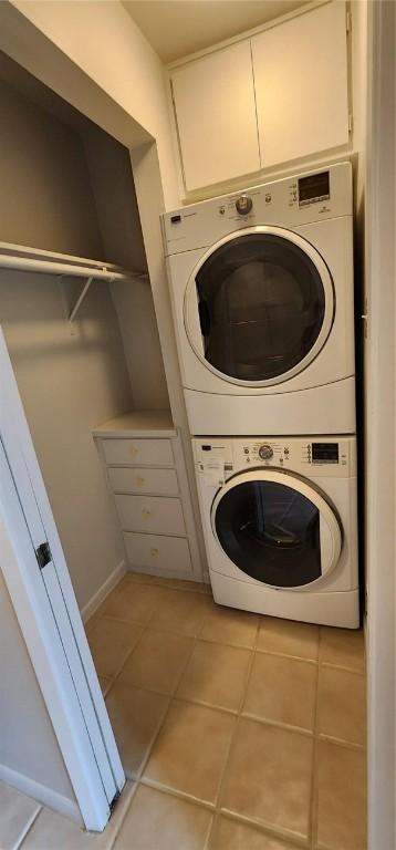 clothes washing area with stacked washer / drying machine and light tile patterned floors