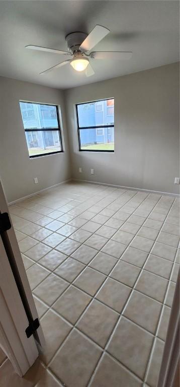 spare room with ceiling fan and light tile patterned floors