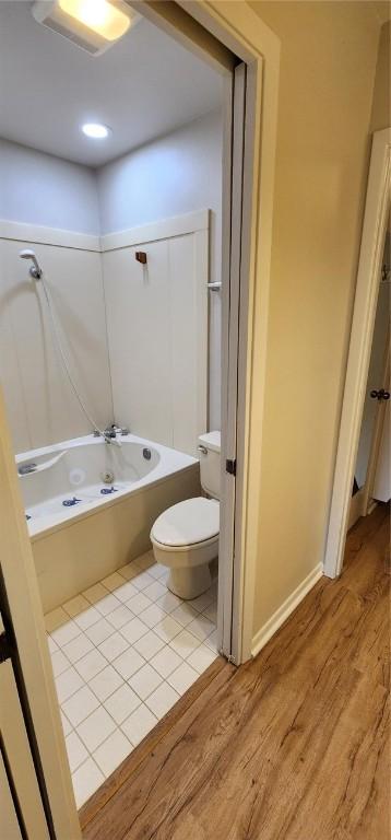 bathroom featuring wood-type flooring, bathtub / shower combination, and toilet