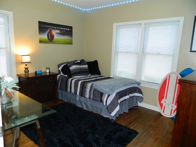 bedroom with dark hardwood / wood-style floors and multiple windows