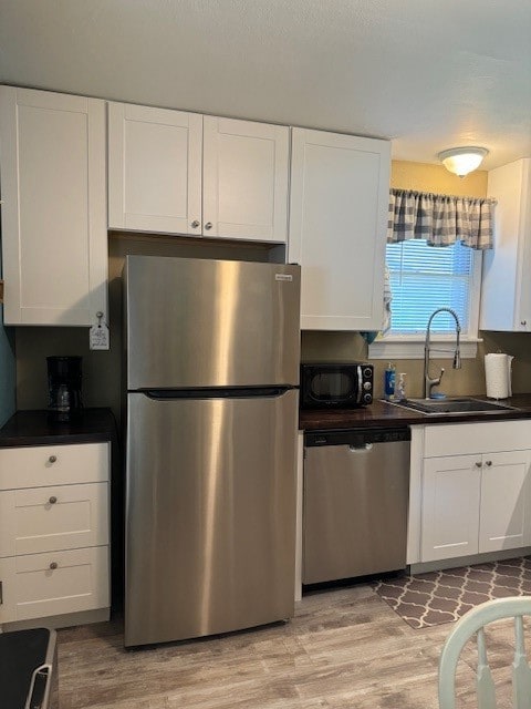 kitchen featuring light hardwood / wood-style flooring, appliances with stainless steel finishes, sink, and white cabinets