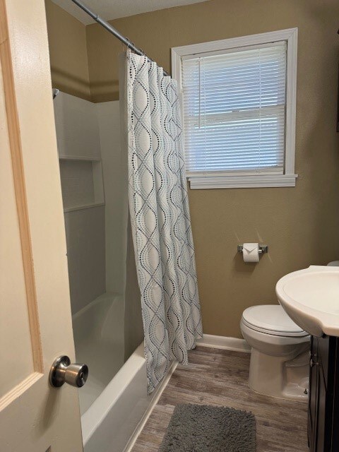 full bathroom featuring shower / bath combo, wood-type flooring, toilet, and vanity