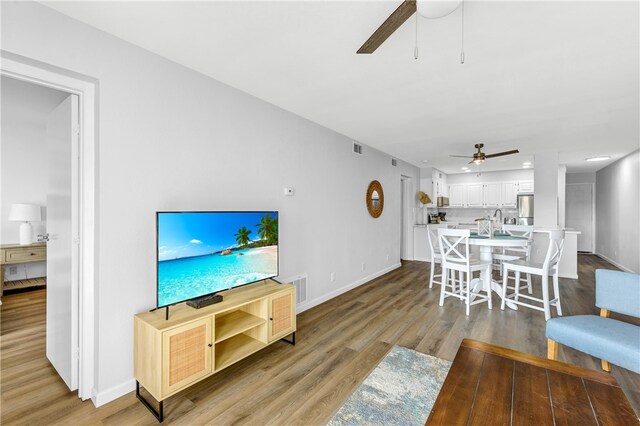 living room with light hardwood / wood-style floors and ceiling fan