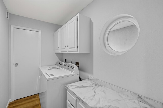 laundry area with cabinets, hardwood / wood-style flooring, and separate washer and dryer