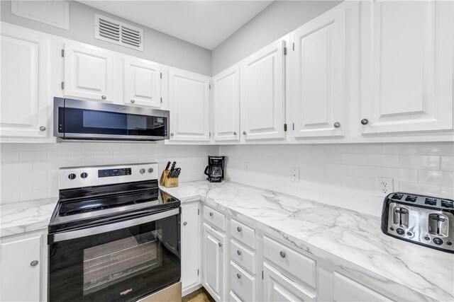 kitchen with light stone countertops, white cabinetry, decorative backsplash, and appliances with stainless steel finishes