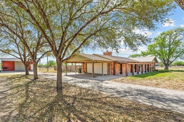 single story home with an attached garage, driveway, and a chimney