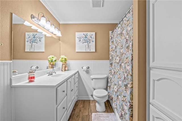full bathroom with visible vents, crown molding, toilet, wainscoting, and wood finished floors