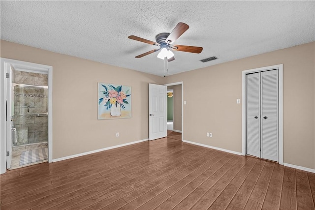 unfurnished bedroom with baseboards, wood finished floors, visible vents, and a textured ceiling