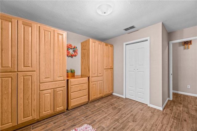 unfurnished bedroom featuring visible vents, wood finished floors, baseboards, and a closet