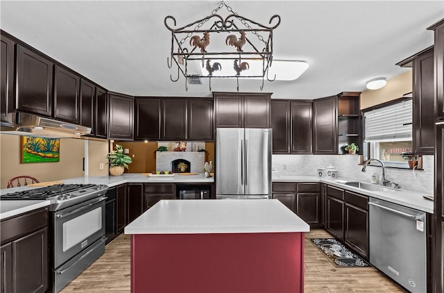 kitchen featuring light wood-style flooring, a sink, under cabinet range hood, stainless steel appliances, and light countertops