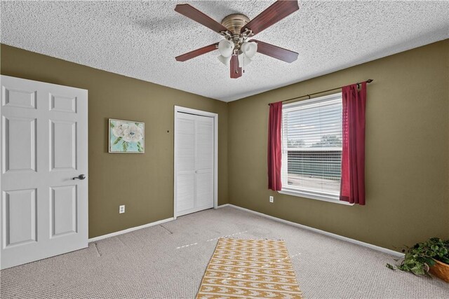 unfurnished bedroom featuring carpet, baseboards, a closet, and a textured ceiling