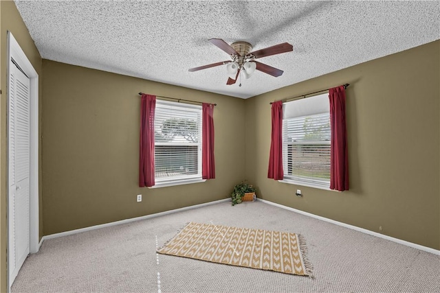 interior space with baseboards, a textured ceiling, carpet floors, and a ceiling fan