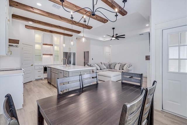 dining room with ceiling fan, beamed ceiling, a healthy amount of sunlight, light hardwood / wood-style flooring, and sink