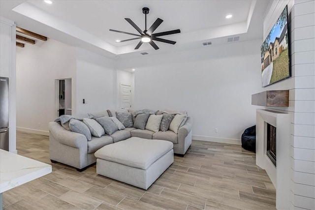 living room with ceiling fan and a tray ceiling