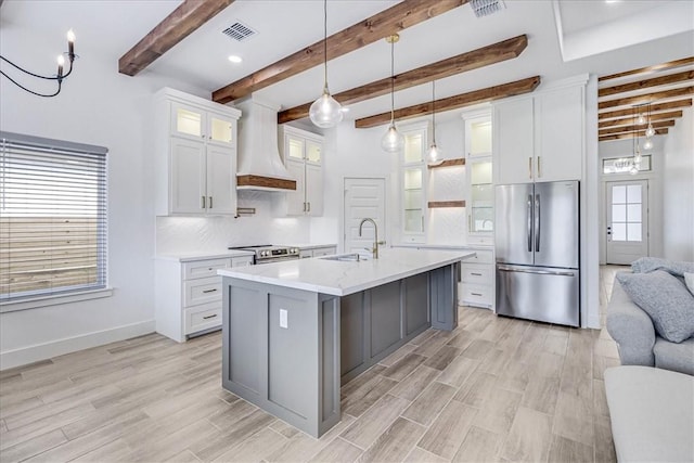 kitchen with beam ceiling, sink, white cabinetry, stainless steel appliances, and custom range hood