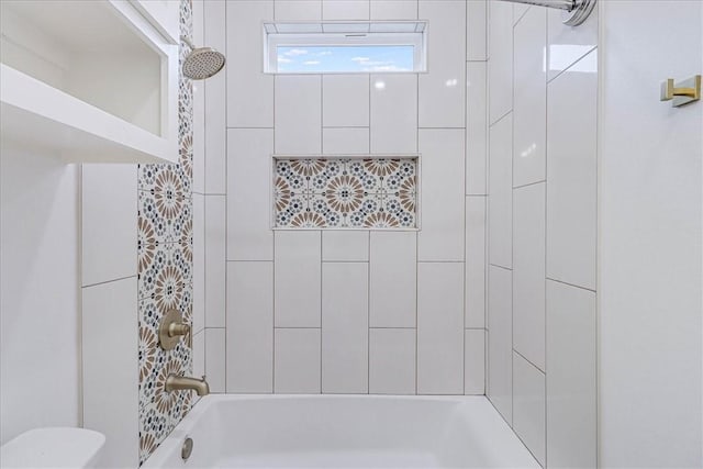 bathroom featuring toilet and tiled shower / bath