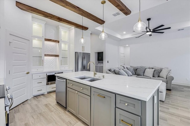 kitchen featuring gray cabinets, sink, hanging light fixtures, appliances with stainless steel finishes, and an island with sink