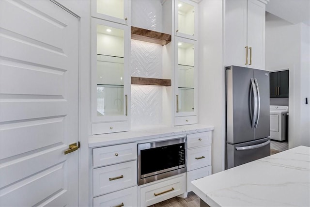 kitchen featuring built in microwave, white cabinets, stainless steel fridge, and light stone countertops