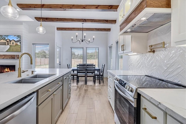 kitchen featuring stainless steel appliances, custom exhaust hood, decorative light fixtures, and sink