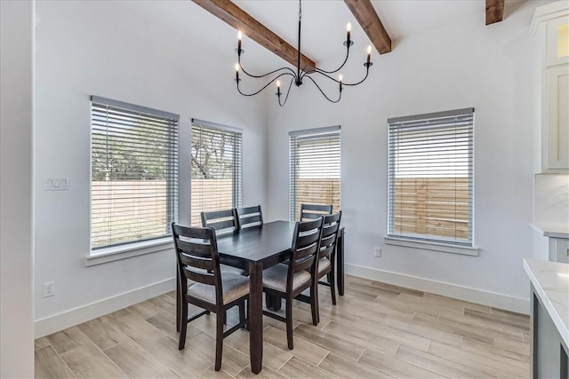 dining space featuring light hardwood / wood-style floors, a wealth of natural light, beam ceiling, and a chandelier