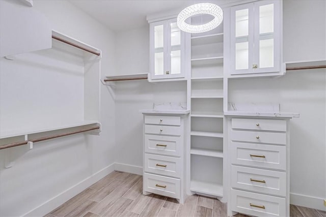 walk in closet with light hardwood / wood-style floors