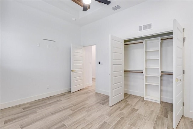 unfurnished bedroom featuring ceiling fan, a closet, and light wood-type flooring