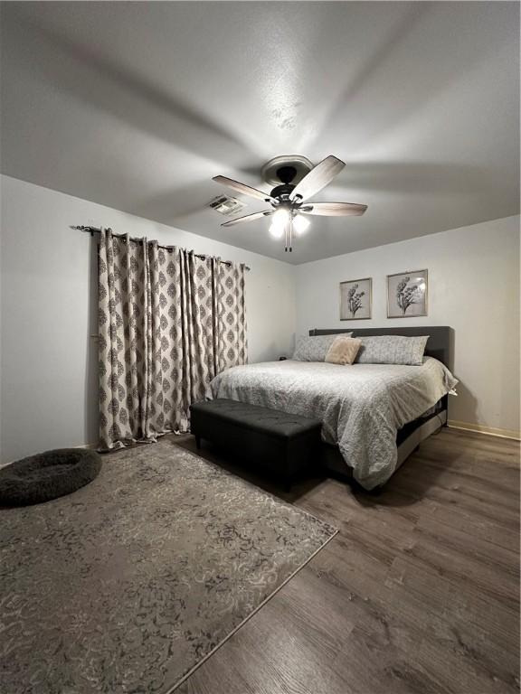 bedroom with dark wood-style floors, ceiling fan, and visible vents